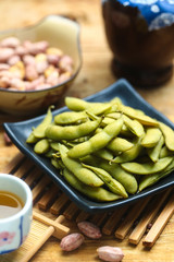 boiled edamame in black plate with rice wine and peanut