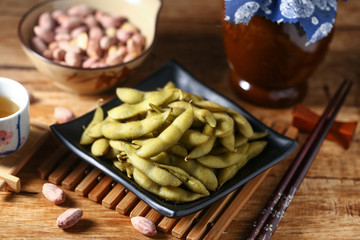 boiled edamame in black plate with rice wine and peanut