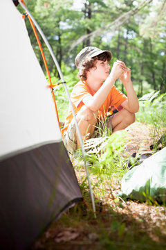 Boy sitting by tent at campsite