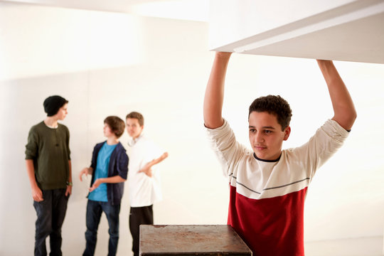 Teenage boy with arms raised and friends in background