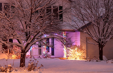 Winter night holiday background. House entrance decorated with glowing lights for winter holidays and lots of snow. Night scene, light blur. Christmas and New Year holiday background.