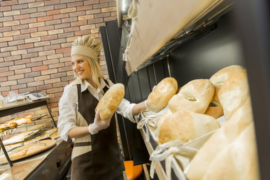 Young woman takes fresh bread from the shelves in a baker shop