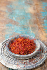 Dried organic red saffron Spice in a stone bowl on wooden background