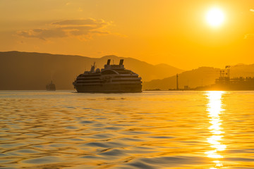 Fototapeta na wymiar A large liner sails in the rays of the sunset along the Boka-Kotorska Bay. Montenegro.