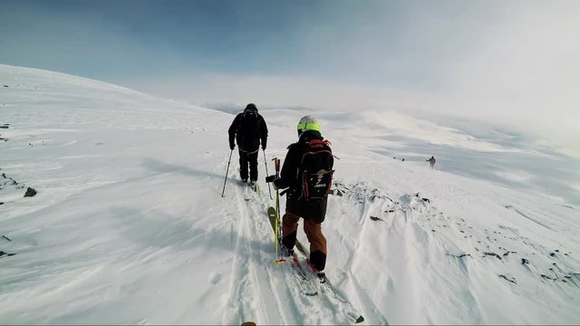 Man skier is on the top of the mountain with friends and they get ready for ski