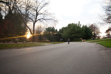 Young boy riding scooter in residential area at sunset