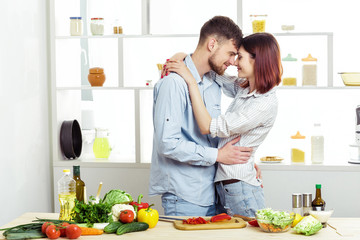 Loving happy couple preparing healthy salad of fresh vegetables in  kitchen