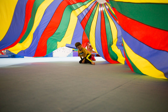 Children playing underneath colourful parachute