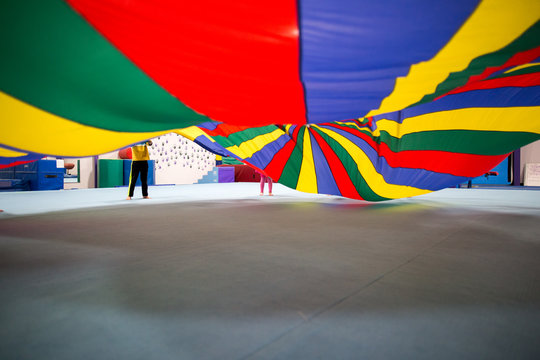 Children playing with colourful parachute, low section