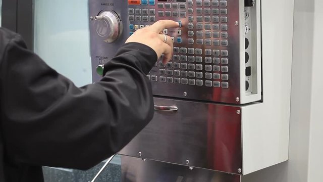 Worker hand on lcd control panel of CNC machine