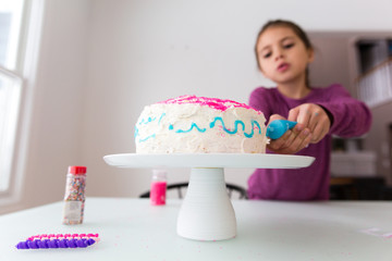 Girl decorating cake with colourful icing