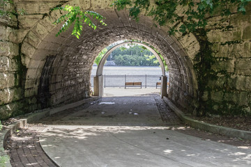 Tunnel on walking path that leads to water.