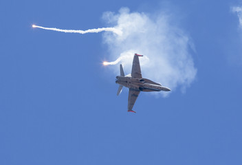 Modern tactical jet fighter shooting flares. White smoke, missiles against a blue sky. Focus point...
