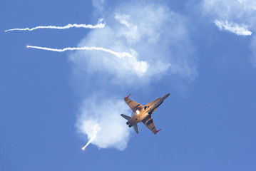 Modern tactical jet fighter shooting flares. White smoke, missiles against a blue sky. Focus point...