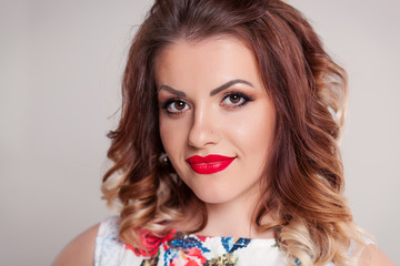 Beautiful Brown-haired model girl on white background . Hairstyle pigtail . Red lips and nails manicure