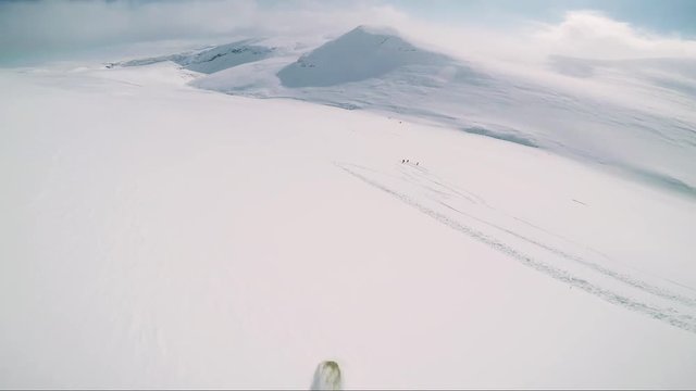 Man skier skiing down mountain and waits with friends in the middle of hill 