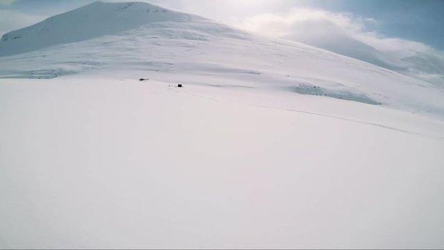 Man skier skiing down mountain with friends to the cabin in the middle of hill 