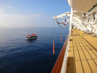 Muster drill on a cruise ship with life boat in the water.