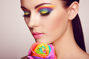 Portrait of beautiful young woman with rainbow rose. Bright colors. Long eyelashes, vivid colorful...