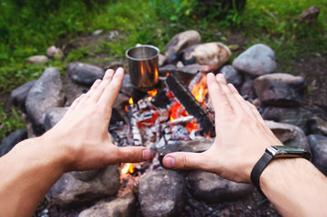 Men's hands are warming around the fire