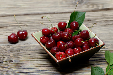 Fresh cherries in a ceramic bowl on old wooden table
