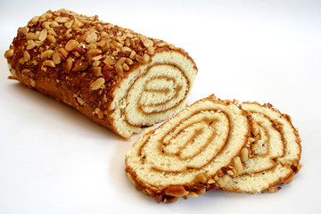 Biscuit roll with jam covered with peanuts on a white background.