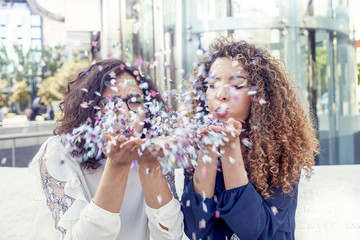 two girls blowing some confetti piece