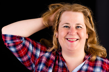 Portrait of a attractive european light overweighted red haired female with red lumberjack shirt - view on head, studio shot in fron of black background