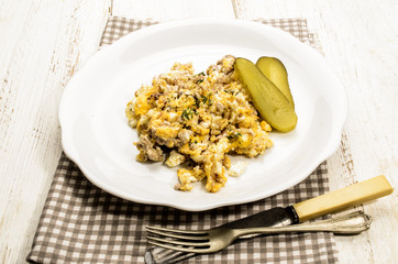 scrambled eggs and grilled pig brain with slice gherkin on a plate
