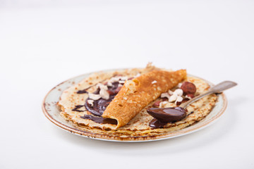 Thin Pancakes with Honey,Chocolate,Hazelnut on a White Background.Tradition,Holiday,Dessert,Breakfast,Pastries.Copy space for Text. selective focus.