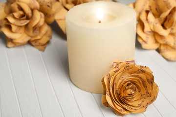 Fototapeta premium Beautiful roses made of music notes with candle on wooden table closeup