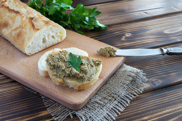 Sandwiches with liver pate and parsley on the brown cutting board
