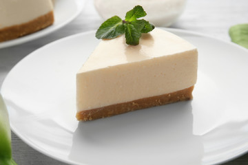 Plate with piece of delicious cheesecake on table