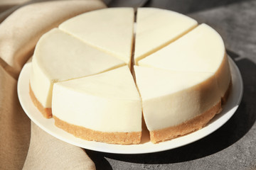 Plate with delicious sliced cheesecake on table