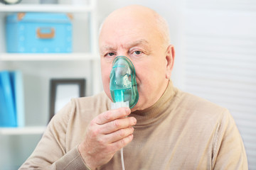 Senior man using asthma machine at home