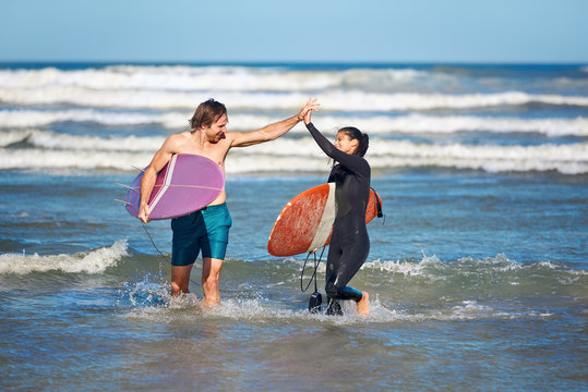 Couple High Five With Surfboards After Surfing - Powered by Adobe