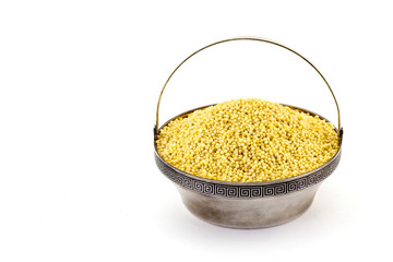Dry millet in silver bowl isolated on white. Spilled millet.