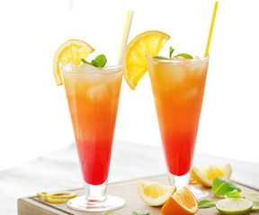 Glasses of Tequila Sunrise cocktail with citrus slices on wooden table