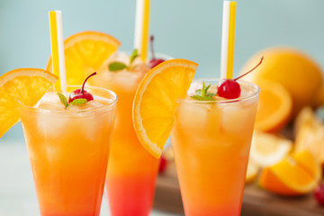 Glasses of Tequila Sunrise cocktail on blurred background, closeup