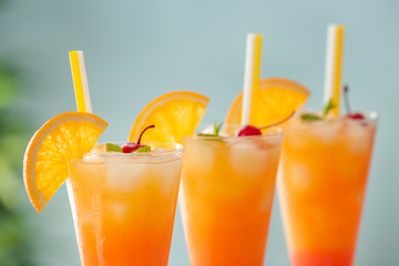 Glasses of Tequila Sunrise cocktail on blurred background, closeup