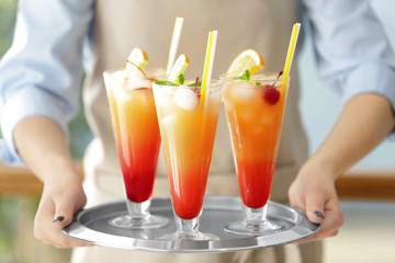 Woman holding tray with glasses of Tequila Sunrise cocktail
