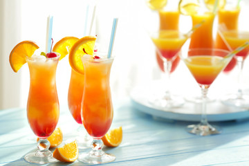 Glasses of Tequila Sunrise cocktail with orange slices on blue table