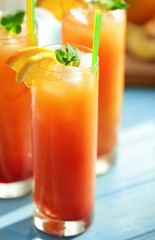 Glass of Tequila Sunrise cocktail with citrus slices on blurred background, closeup