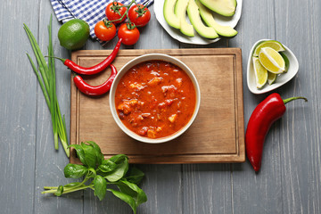 Bowl with delicious chili turkey and fresh vegetables on wooden table