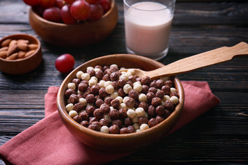 Bowl with delicious cereal balls on wooden table