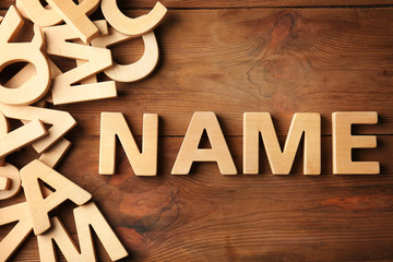 Word NAME on wooden background. Concept of choosing baby name