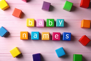 Color cubes with words BABY NAMES on wooden background. Concept of choosing baby name