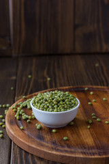 Organic mung beans on white ceramic bowl over wooden background.