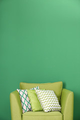 Cozy armchair with pillows on green background