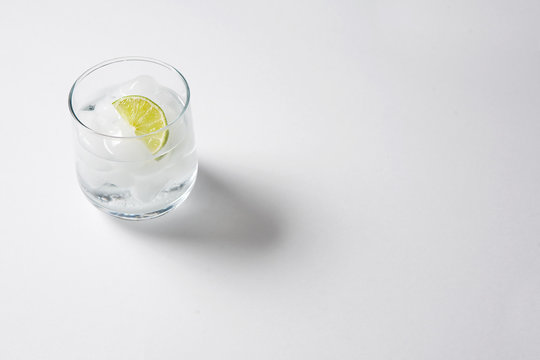 Gin and Tonic with ice and slice of lime on a white table. GnT.